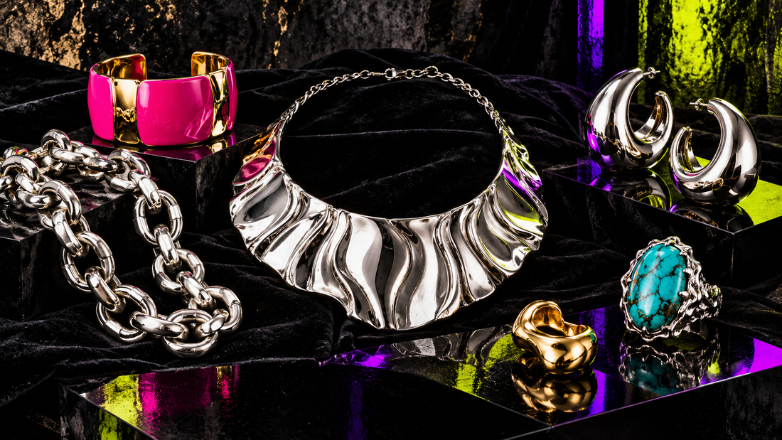Tarnished and freshly polished sterling-silver rings, hoop earrings, chain, and pendant arranged across black velvet beside a polishing cloth.