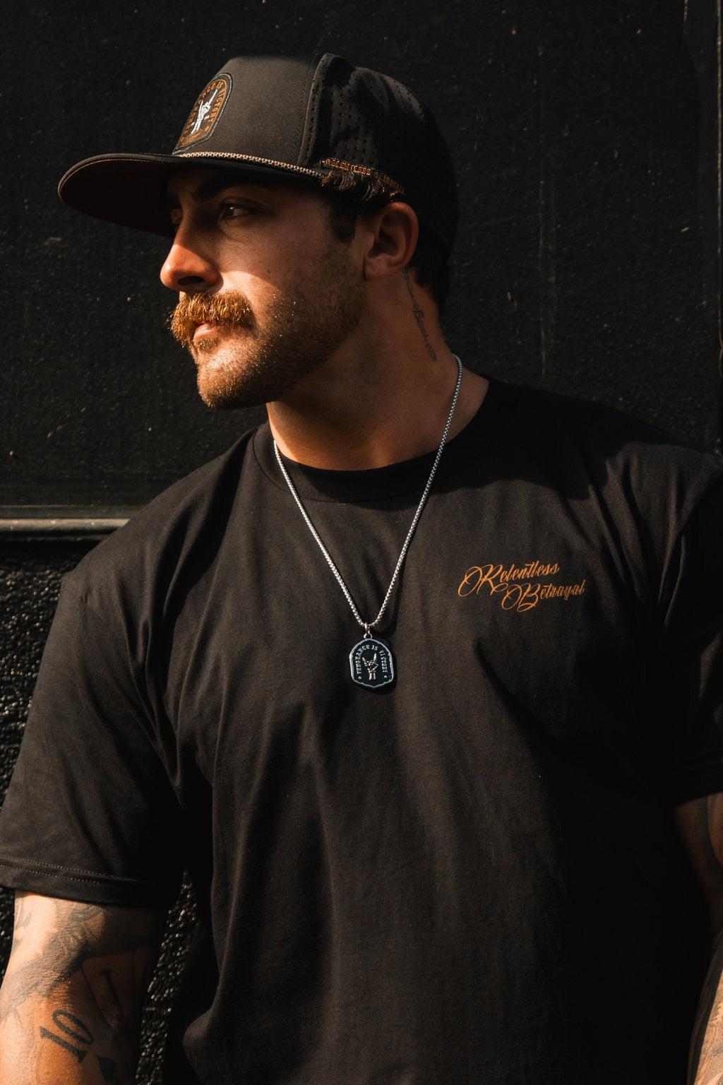 Vengeance Necklace: black shield-shaped pendant with skeletal hand and VENGEANCE IS VICTORY lettering, worn on a model.