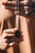 Vengeance Necklace: black shield-shaped pendant with skeletal hand and VENGEANCE IS VICTORY lettering, held by its chain.