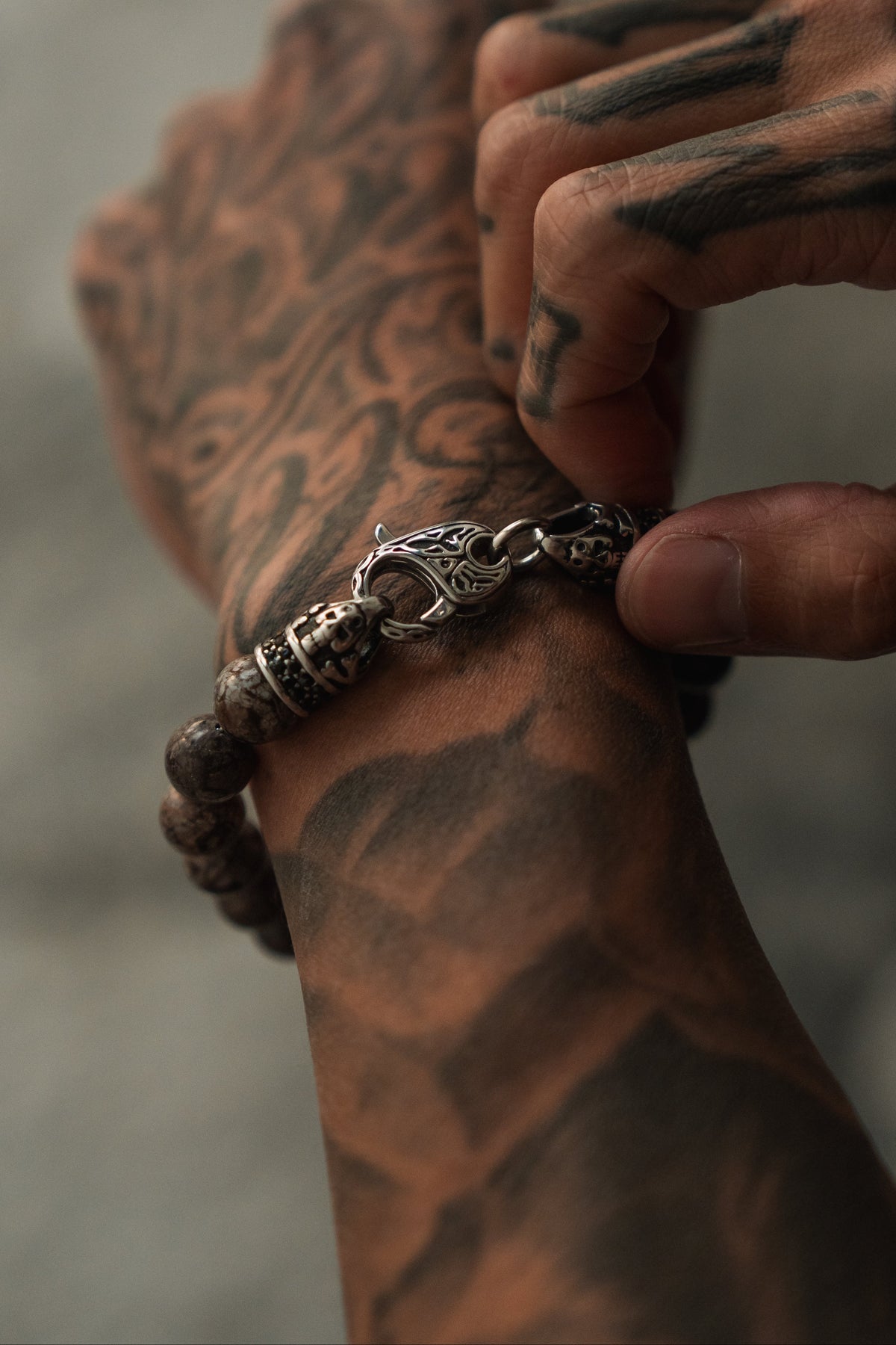 The Black Seal Bracelet: brown speckled round beads with decorative silver-tone clasp, clasp detail on a wrist.