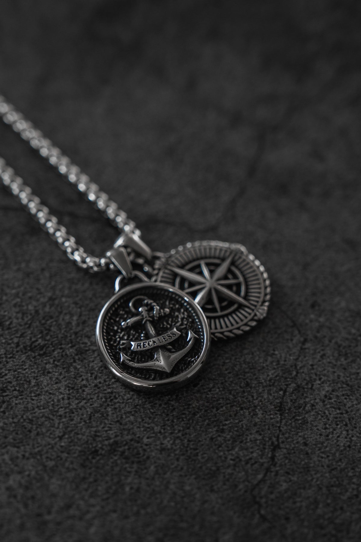 Reckless Soul Necklace: paired round anchor and compass-rose pendants on a silver-tone chain, pendant close-up.
