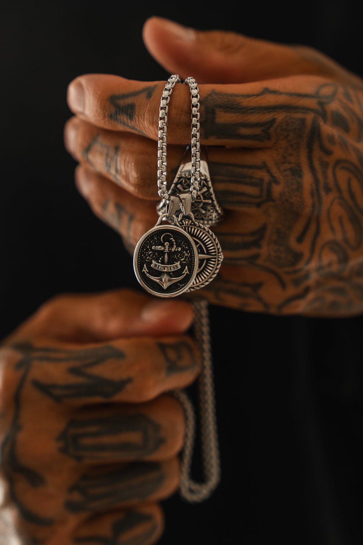 Reckless Soul Necklace: paired round anchor and compass-rose pendants on a silver-tone chain, held by its chain.