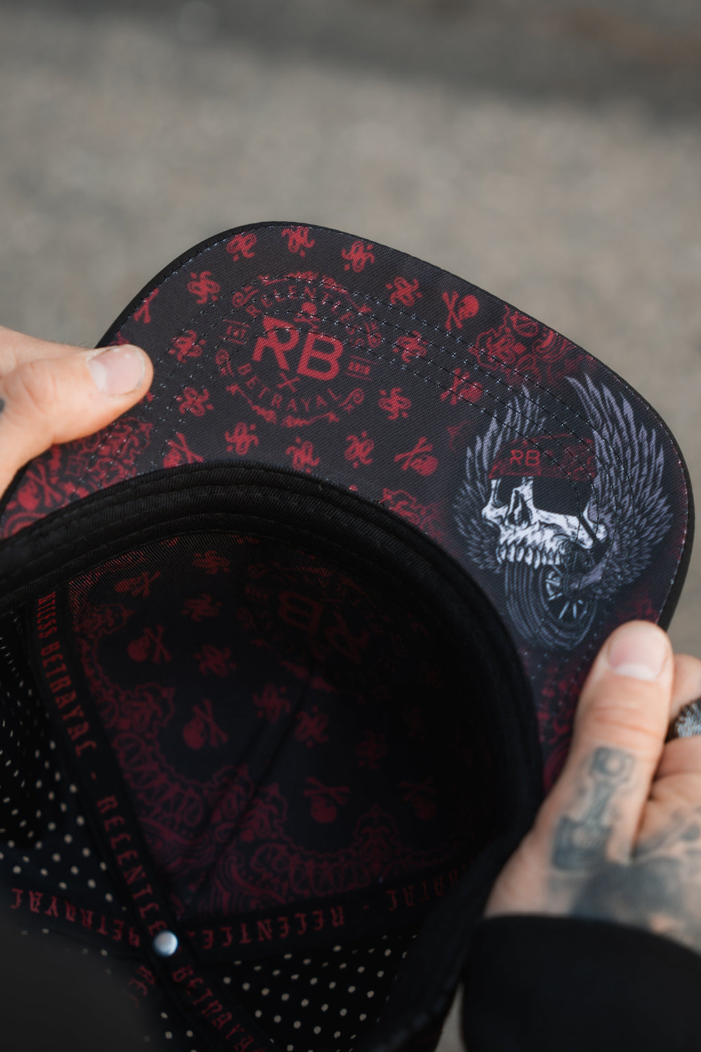 All Gas No Brakes Premium Snapback: black cap with red bandana-style print, skull patch and red rope trim, underside held in hands.