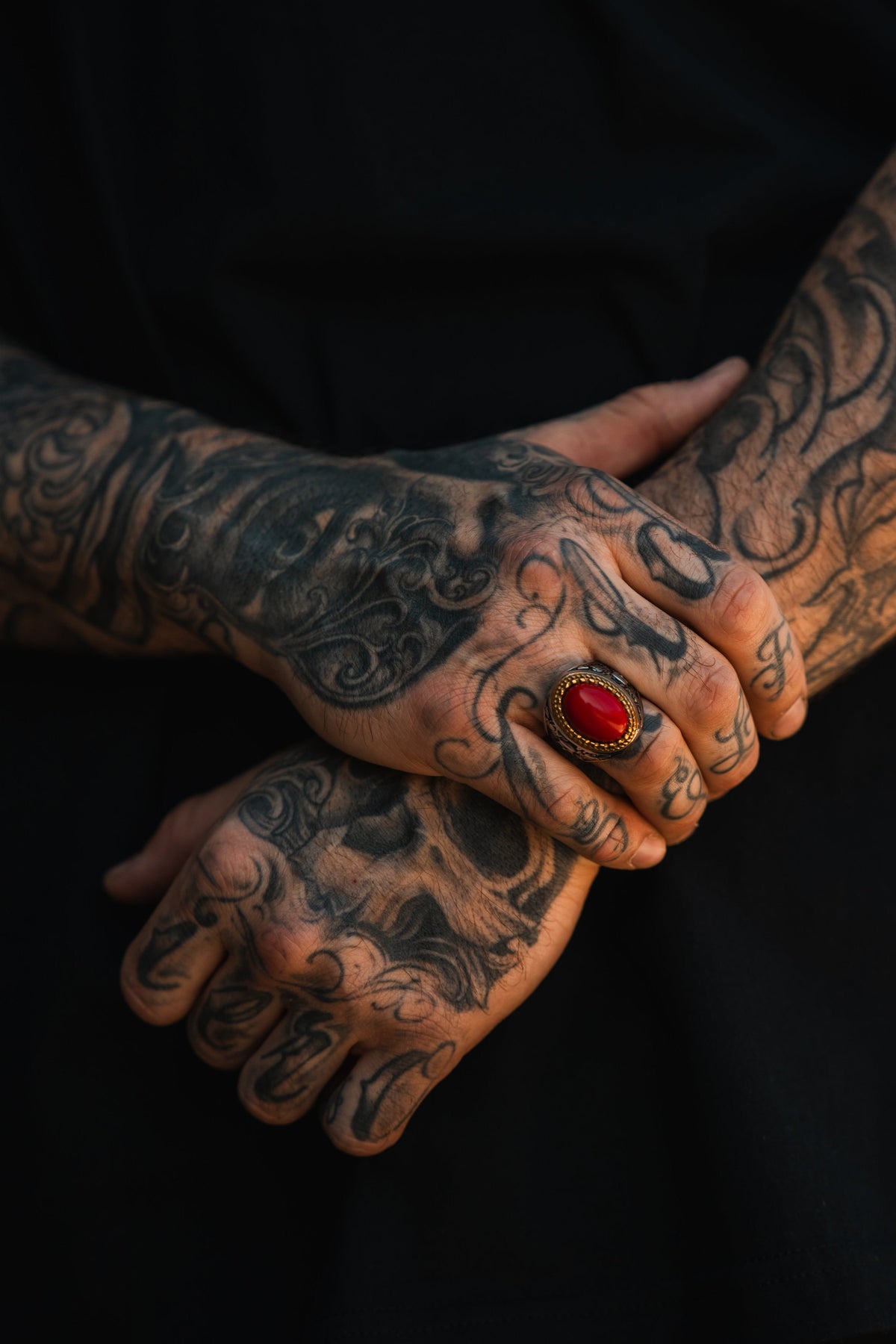 Burning Rose Ring: oval red center, gold-tone border and detailed silver-tone band, worn on clasped hands.