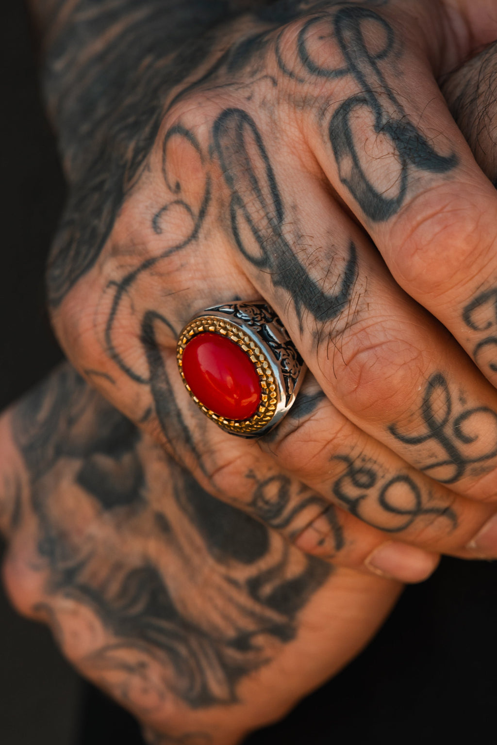Burning Rose Ring: oval red center, gold-tone border and detailed silver-tone band, close-up on a hand.