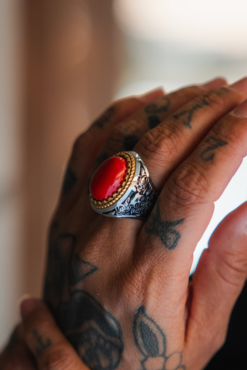Burning Rose Ring: oval red center, gold-tone border and detailed silver-tone band, angled view on a finger.