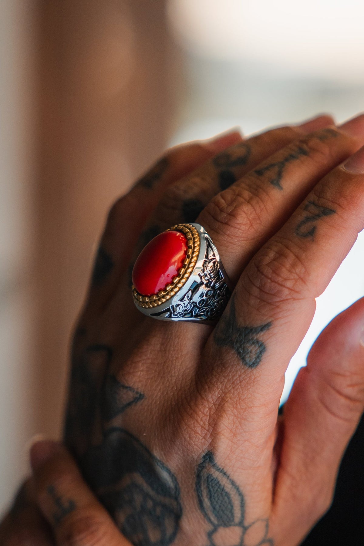 Burning Rose Ring: oval red center, gold-tone border and detailed silver-tone band, angled view on a finger.