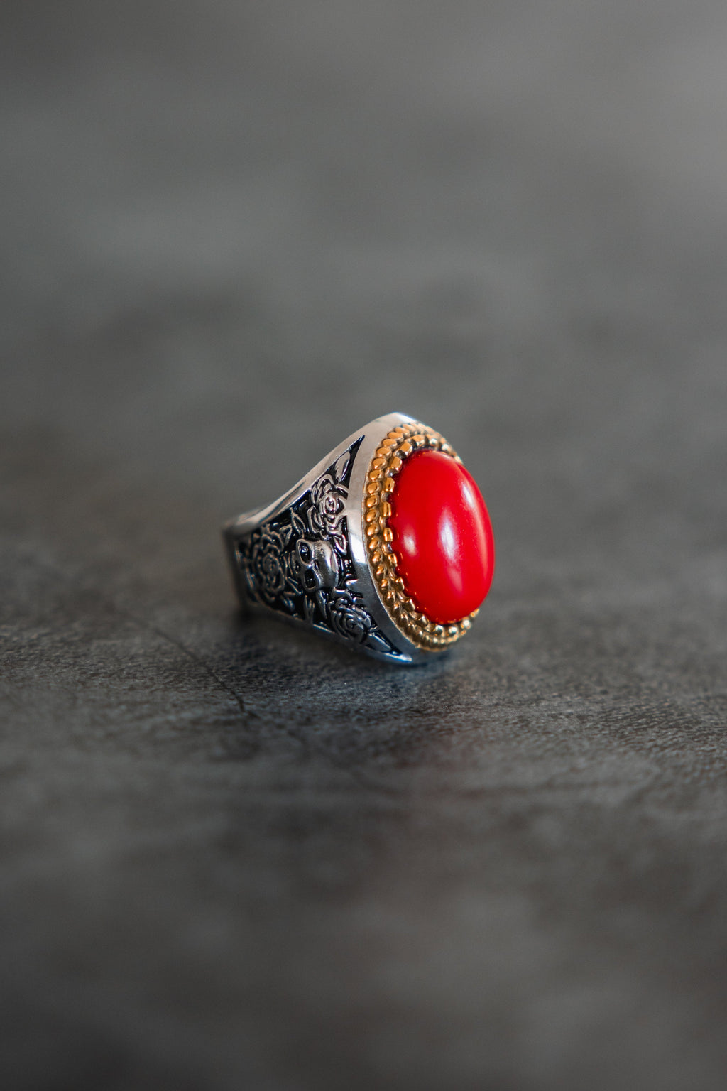 Burning Rose Ring: oval red center, gold-tone border and detailed silver-tone band, angled product view.