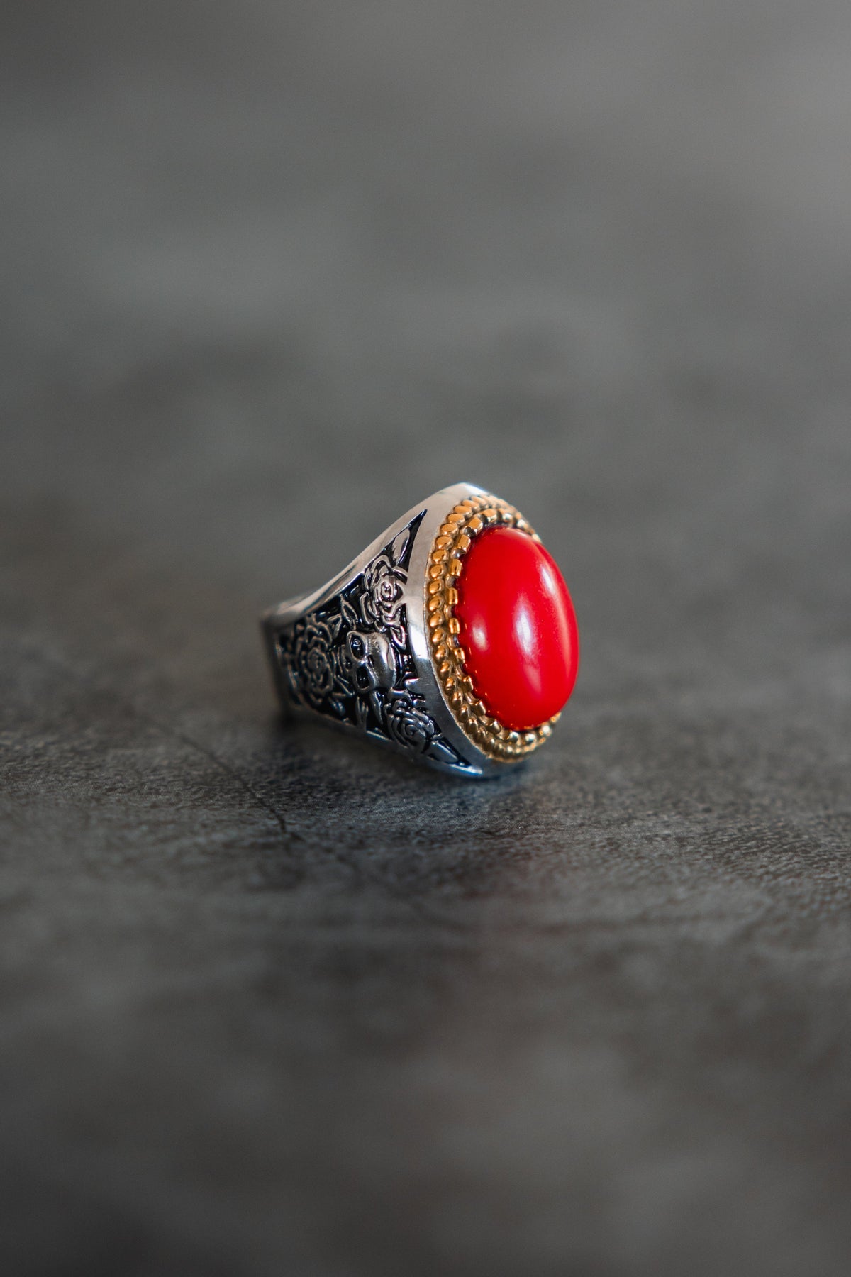 Burning Rose Ring: oval red center, gold-tone border and detailed silver-tone band, angled product view.