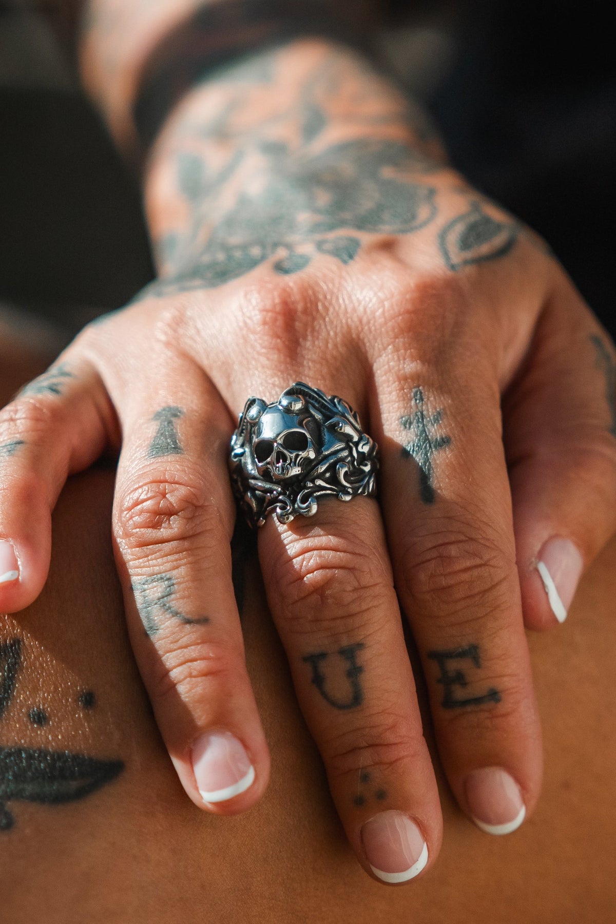 Gravewater Ring: sculpted skull with ornate curling side details, worn on a hand.