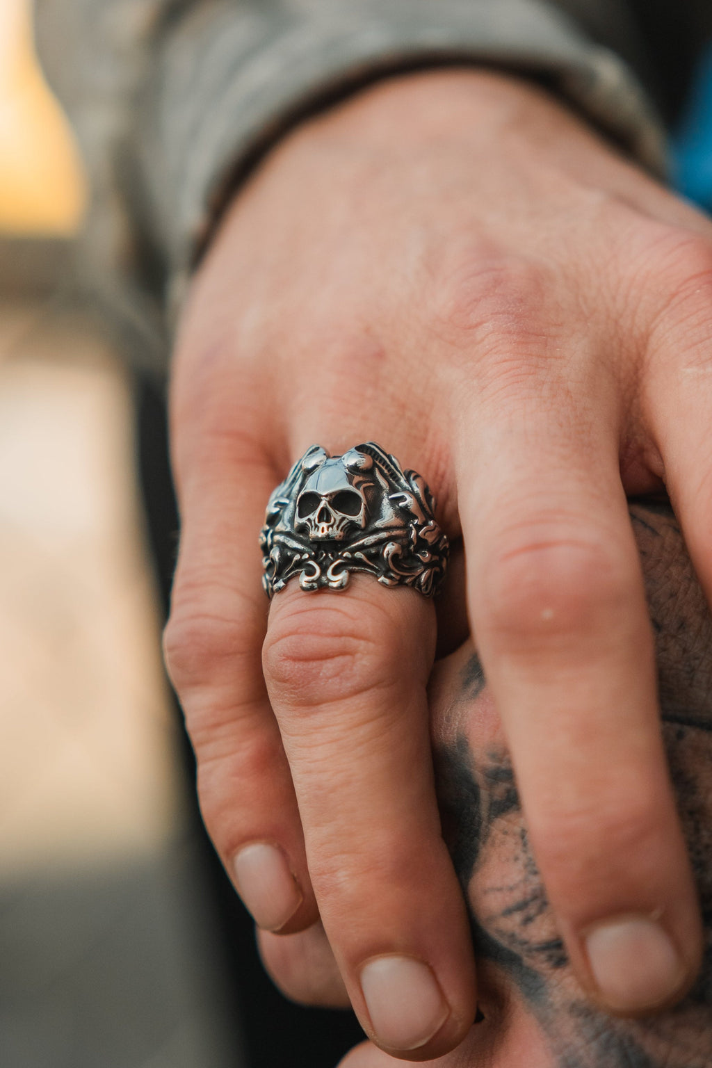 Gravewater Ring: sculpted skull with ornate curling side details, worn on a hand.