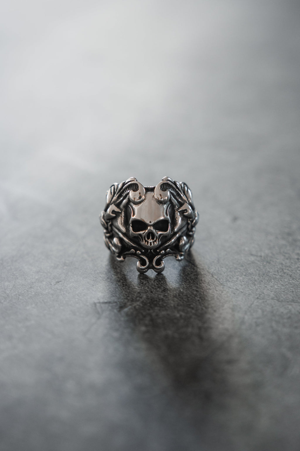 Gravewater Ring: sculpted skull with ornate curling side details, front view.