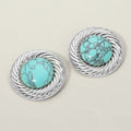 Rhodium-tone stud earrings with a round turquoise-color stone center framed by a textured swirl rim