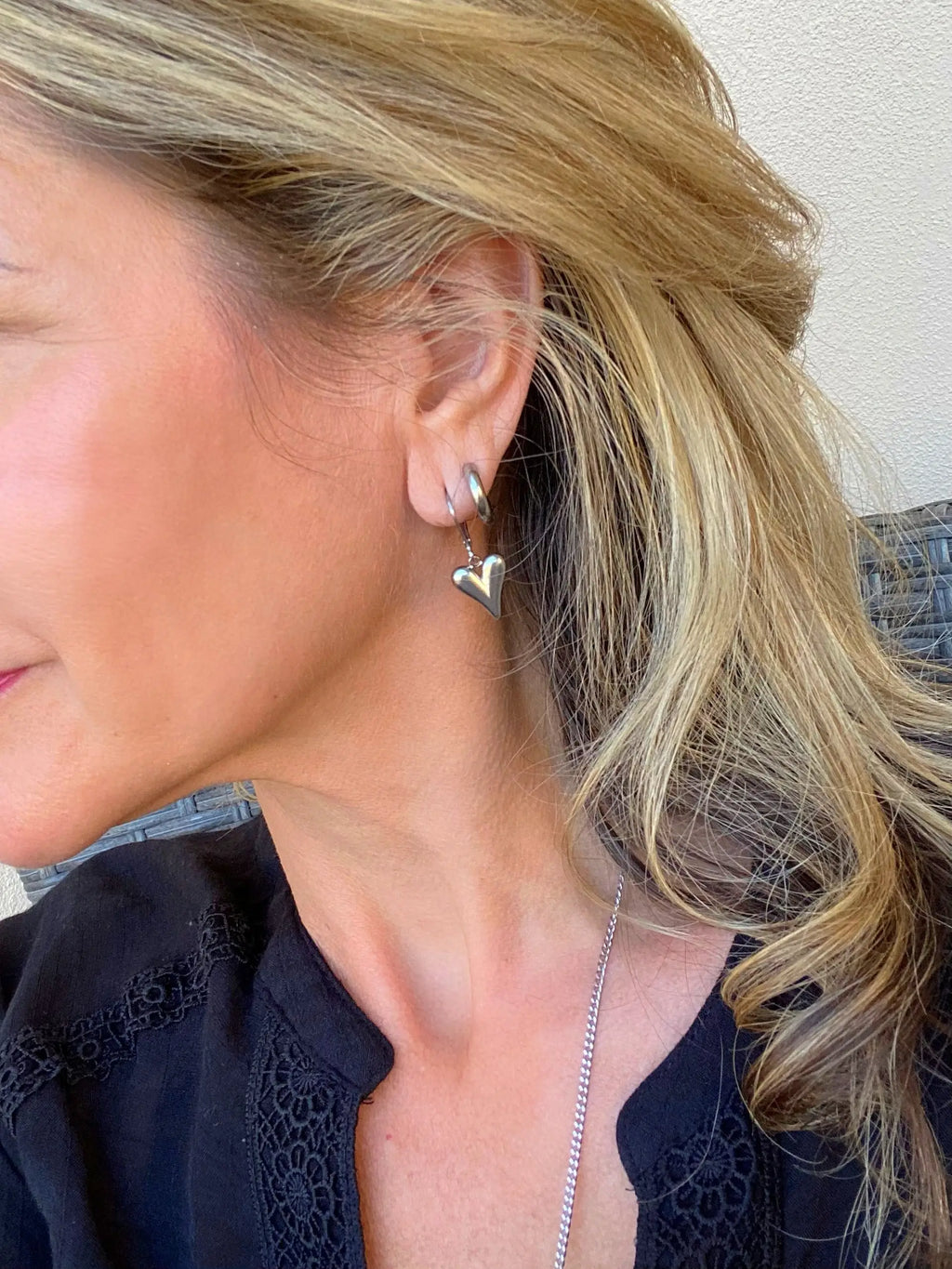 Silver-Tone Heart Earrings worn on an ear