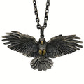 Falcon pendant with wings spread on a metal chain, shown against a white background with gold-tone beak and talon accents visible