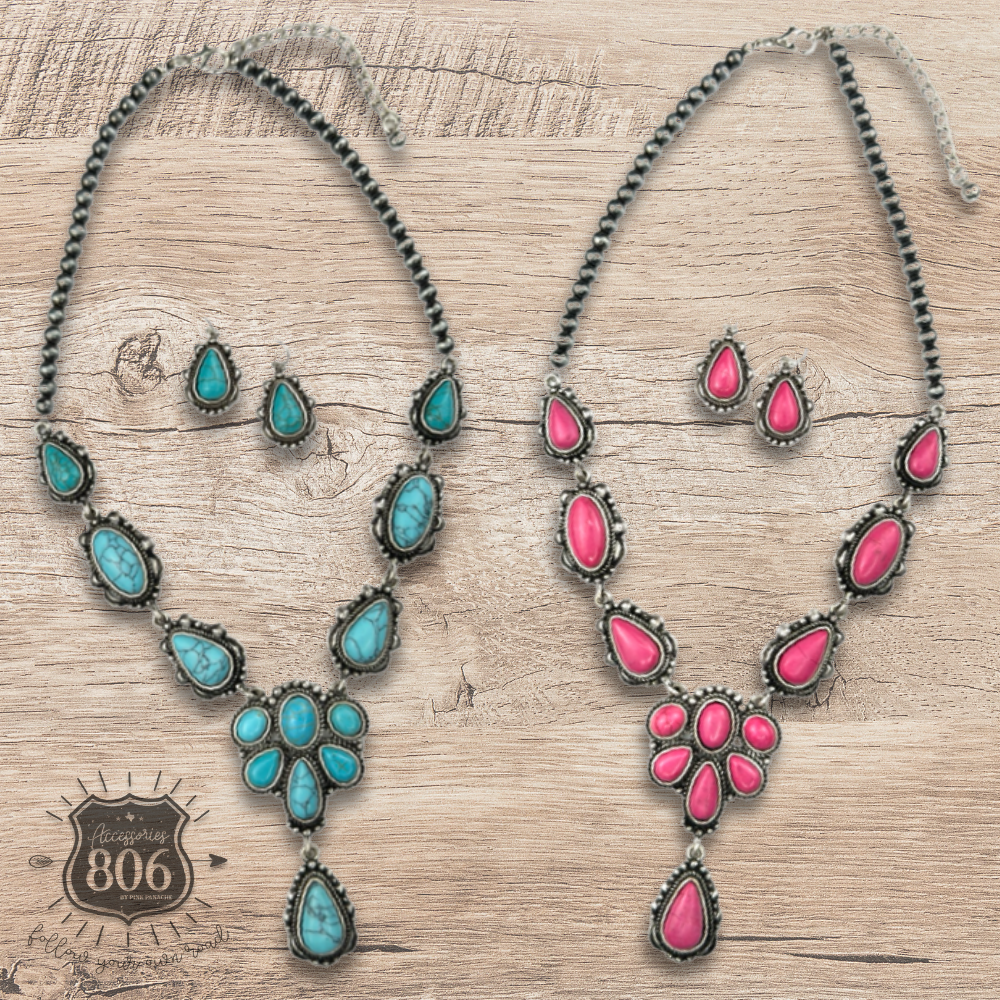 Two concho necklace and earring sets side by side on a wood surface: one with turquoise-color stone clusters, one with fuchsia-pink stone clusters, both on a dark bead chain with matching teardrop stud earrings