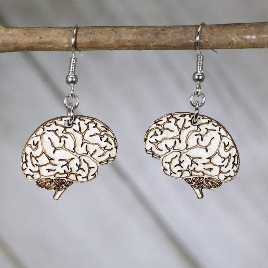Pair of wood-etched brain silhouette earrings hanging from a branch