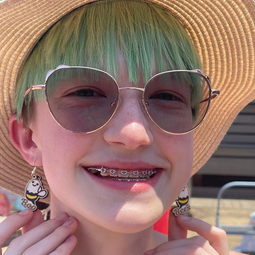Model wearing both Boo Bees ghost-bee earrings, one reading 'Boo' and one reading 'Bees'