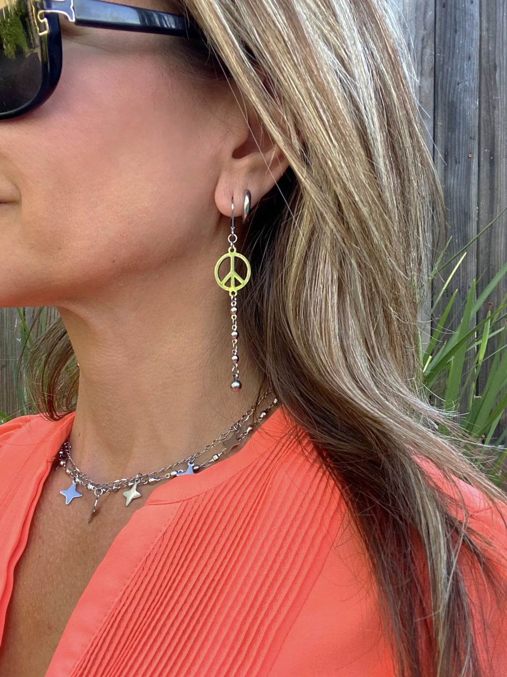 Model wearing the Peace Sign Drop Earrings in profile, layered with necklaces