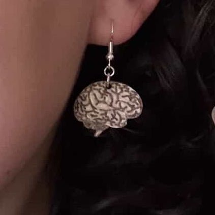 Close-up of a wooden brain-shaped dangle earring worn on the ear