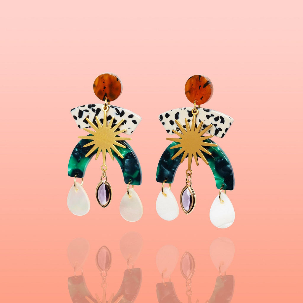 Pair of Sunburst Shell Drop Statement Earrings laid flat, showing the tortoiseshell-effect stud, black-and-white spotted arc, gold sunburst, green marbled arch, and shell and stone drops